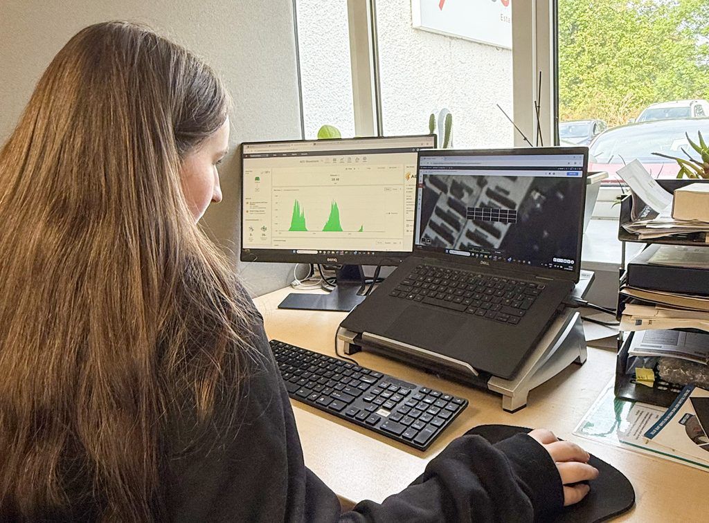 A young woman on work experience at aes renewables at a desk working on a laptop screen of technical solar drawings